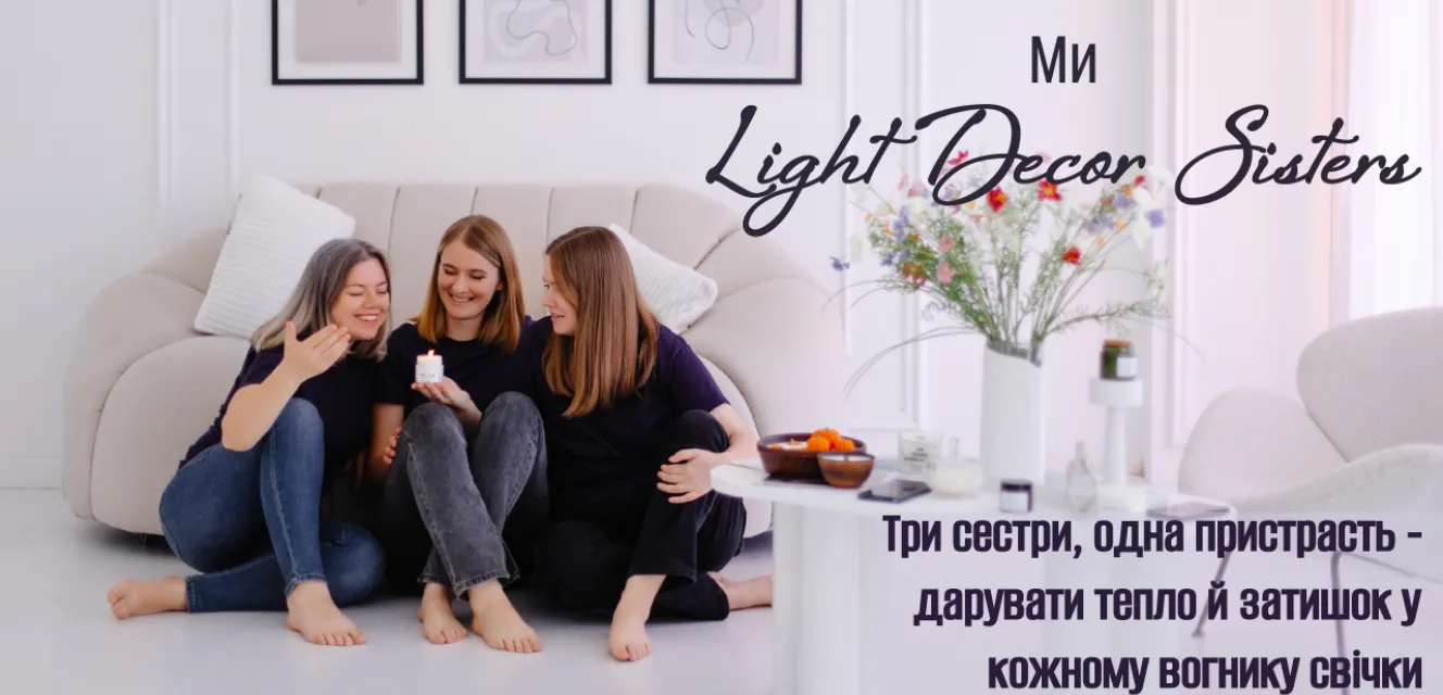 Три сестри сидять разом у світлій кімнаті, усміхаються та тримають у руках ароматичну свічку. Атмосфера затишку, тепла та гармонії.